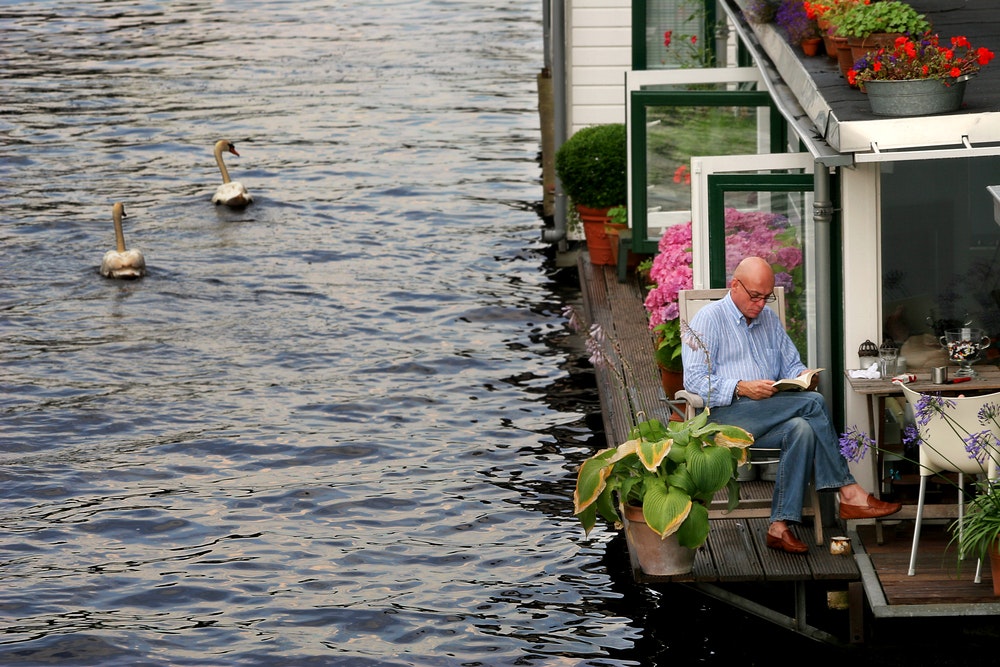 Un uomo legge un libro all'aperto su una casa galleggiante.