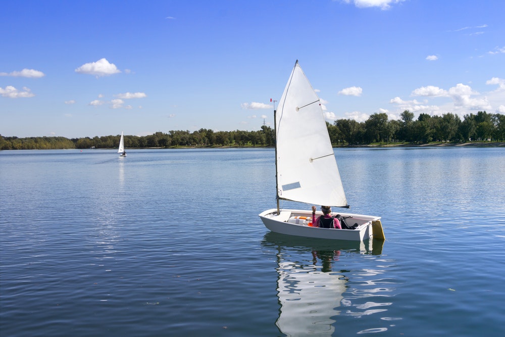 Small white boat sailing on the lake on a beautiful sunny day