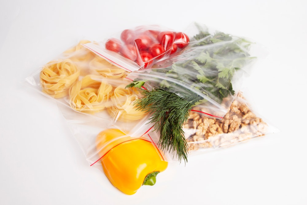 Embalagem de legumes, verduras e nozes num fecho de correr sobre fundo branco
