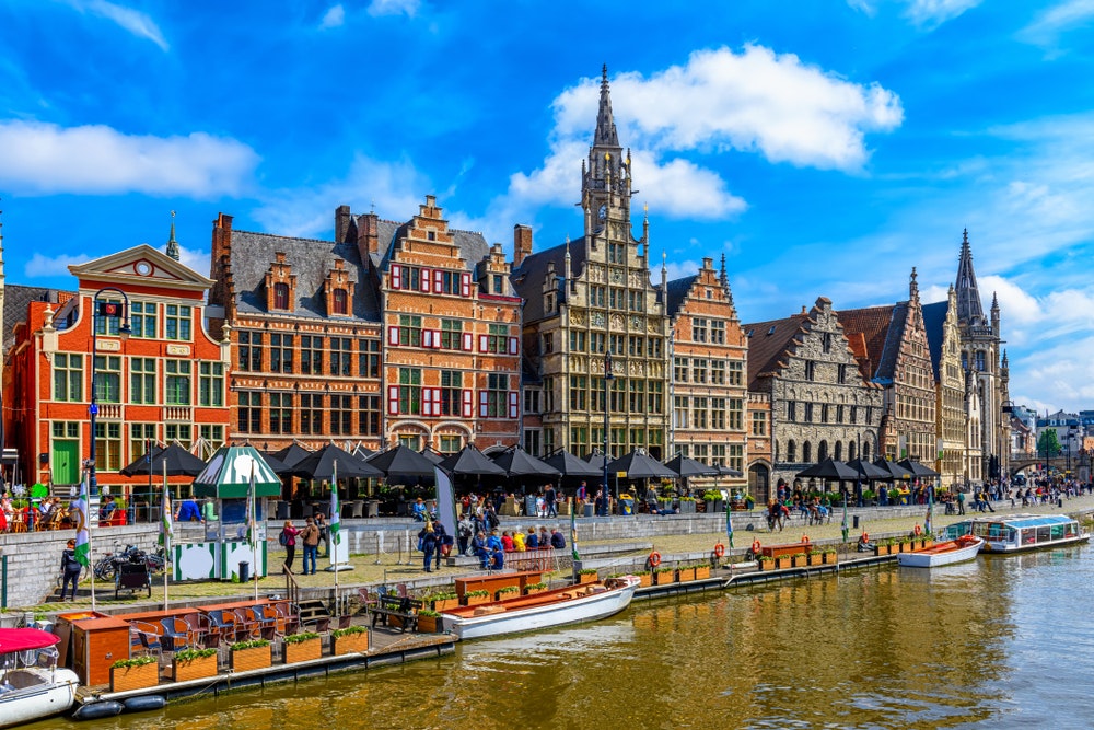 Den pittoreska staden Gent, Belgien med sin kanal, båtar och vattnet.