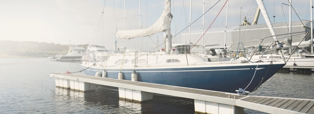 Elegáns és modern vitorlás tiszta időben egy jachtkikötő mólóján kikötve.