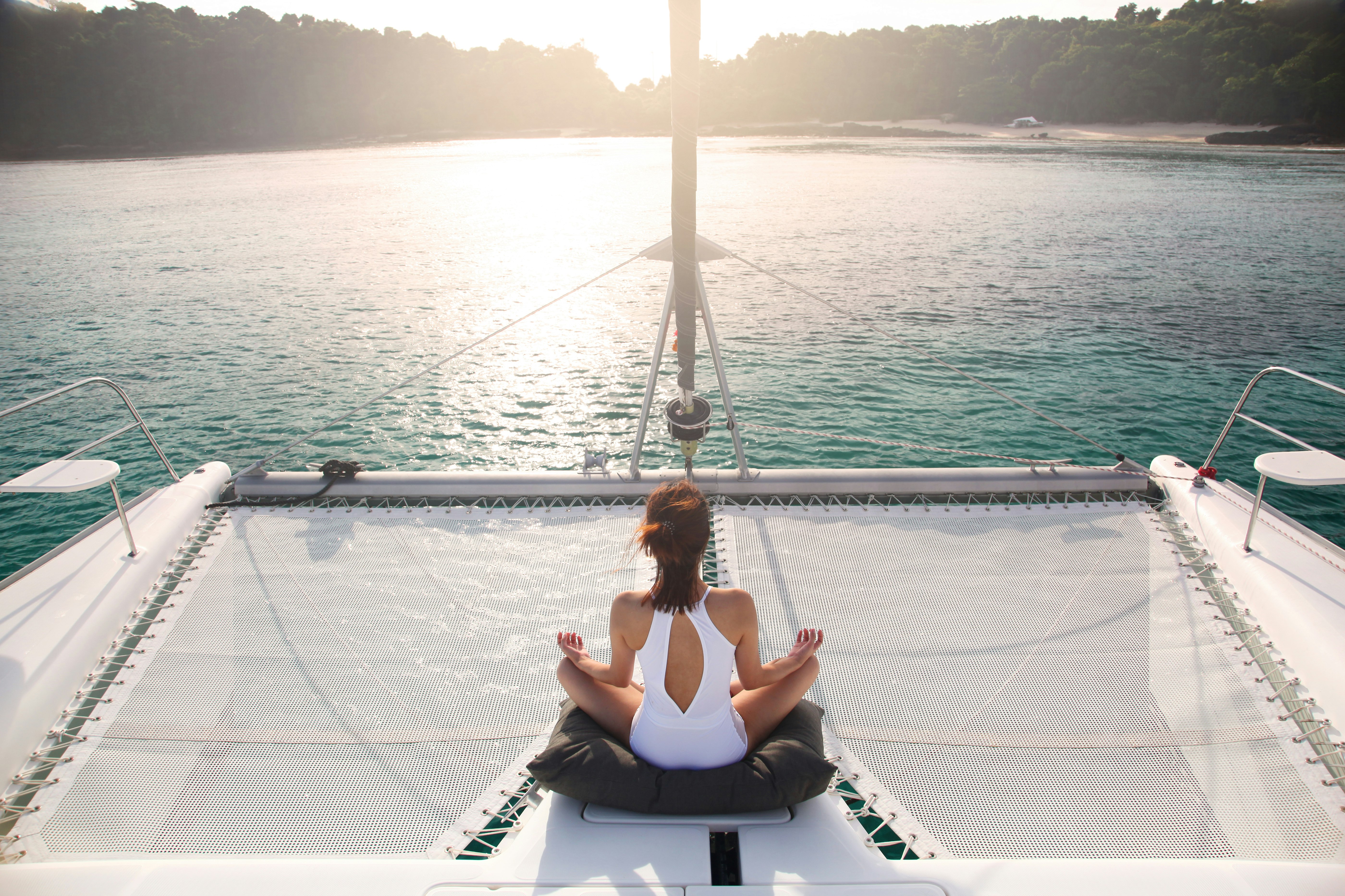 Woman peacefully meditating on a Catamaran 