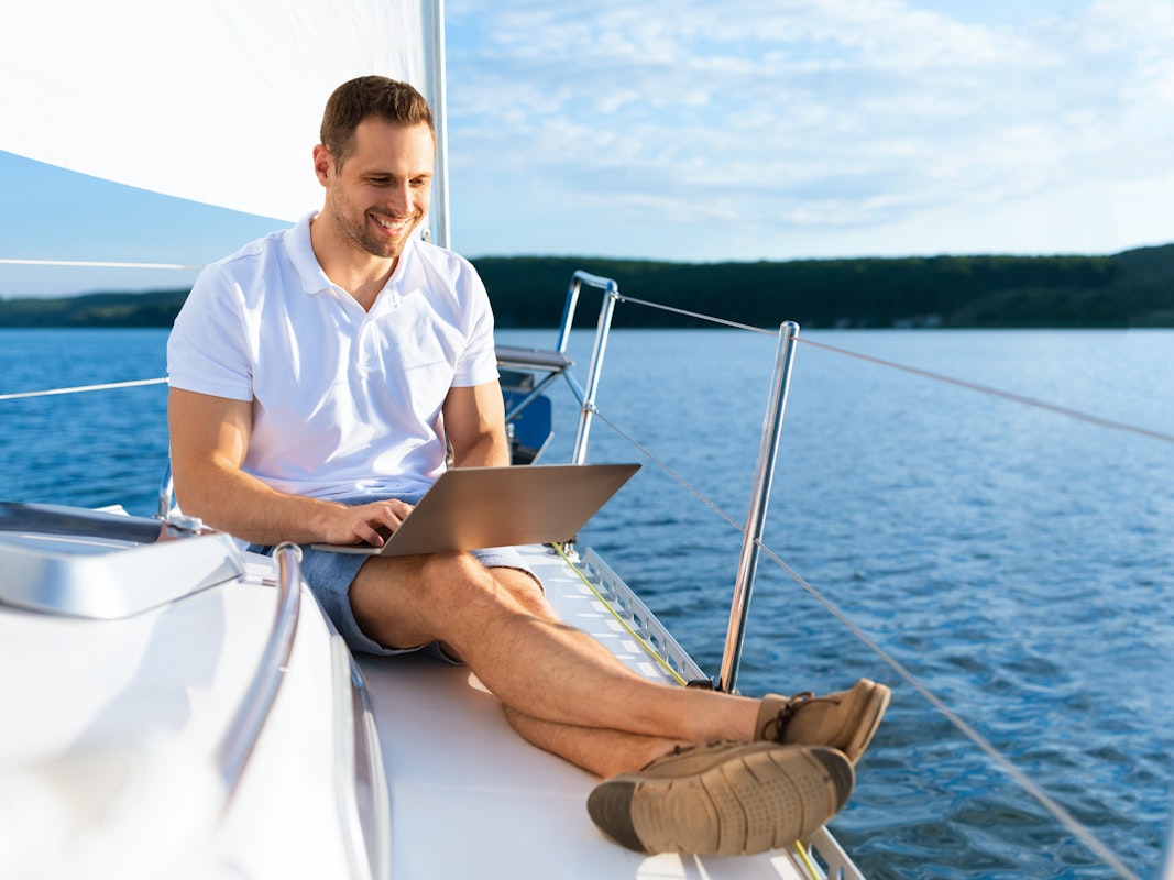 Man with laptop on the bow of the boat