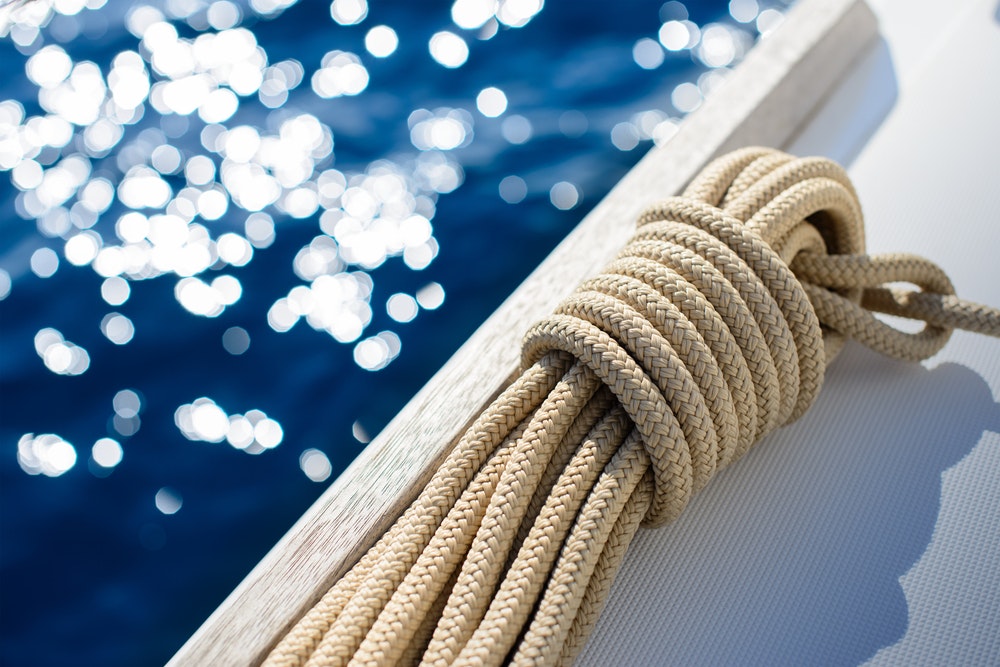 Detail of yachting - Rope on deck/board with reflection of water and sun in the background