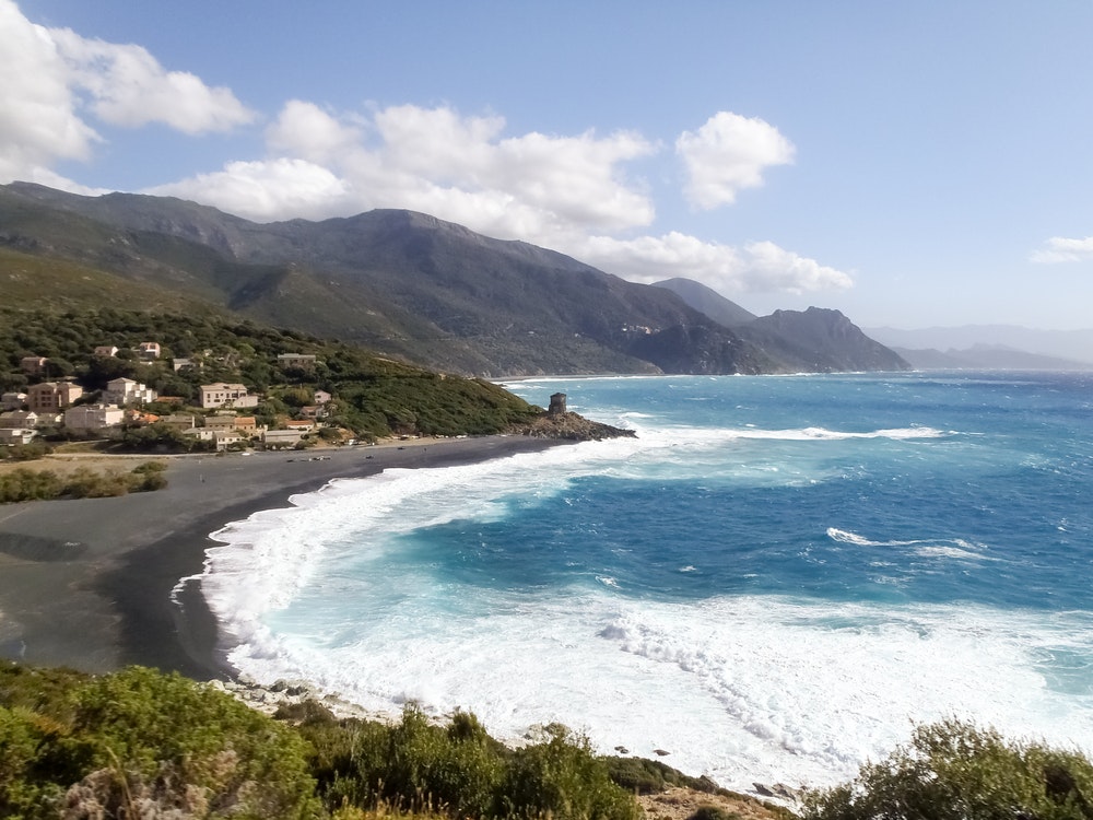 Pobrežie ostrova Korzika, pláž Nonsa, rozbúrené more plné peny kvôli vietru mistrál.