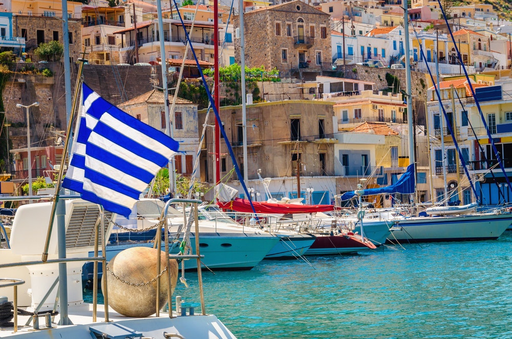 Bandiera greca bianca e blu e vento in un porto greco pieno di navi, Kos, Grecia