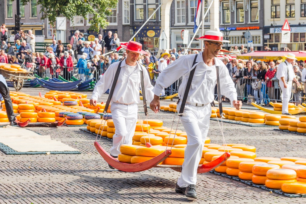 Portterit, joissa on paljon juustoa kuuluisalla hollantilaisilla juustomarkkinoilla Alkmaarissa, Hollannissa, Waagplein-aukiolla.