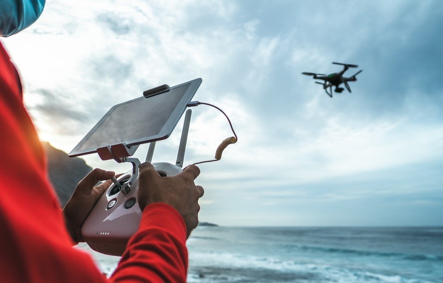Hombre controlando un dron sobre el mar