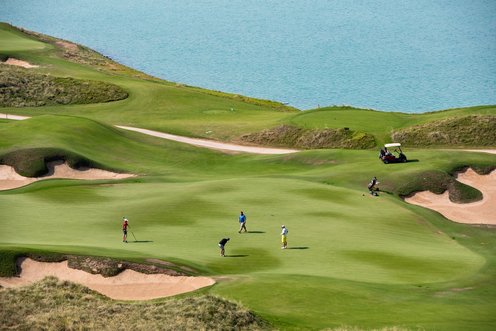Station de golf et joueurs au bord de la mer.