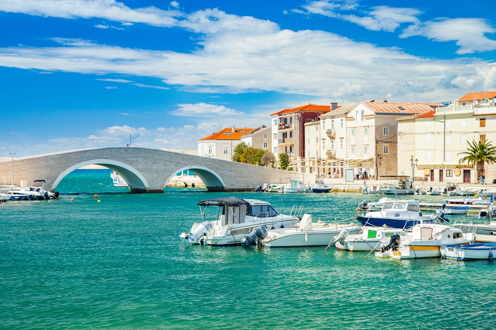 Kaunis Pagin kaupunki Adrianmerellä Dalmatiassa, Kroatiassa, vanha kivisilta, ranta ja satama veneineen