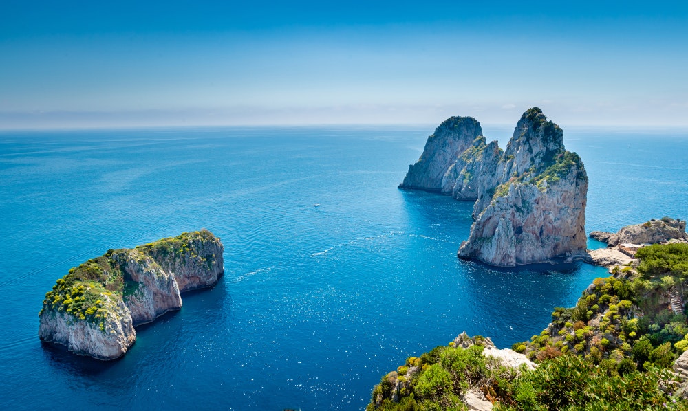 Blick auf die Faraglioni-Felsen von einem Pass an der Küste von Capri, Italien.