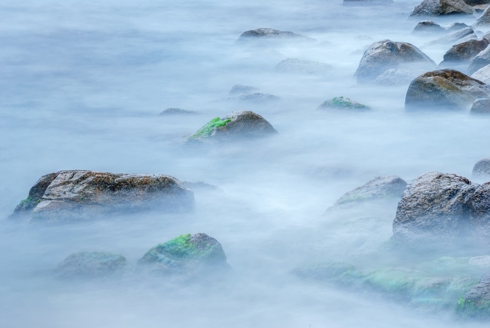 Des rochers sur le rivage dans le brouillard.