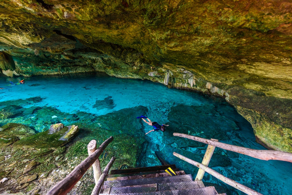 Cenote Dos Ojos a Quintana Roo, vicino a Tulum, nella penisola dello Yucatán in Messico. Le persone nuotano e fanno snorkeling nell'acqua limpida e blu. 