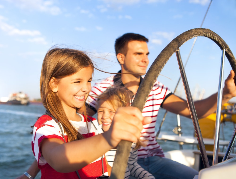 Caucasian male and two children driving a boat
