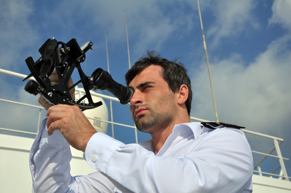 navigátor so sextantom na hliadke na námornej lodi