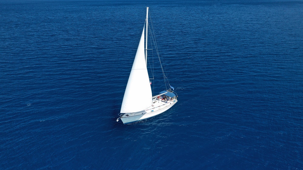 Aerial drone photo of beautiful sail boat with white sails, sailing open ocean deep blue Mediterranean sea