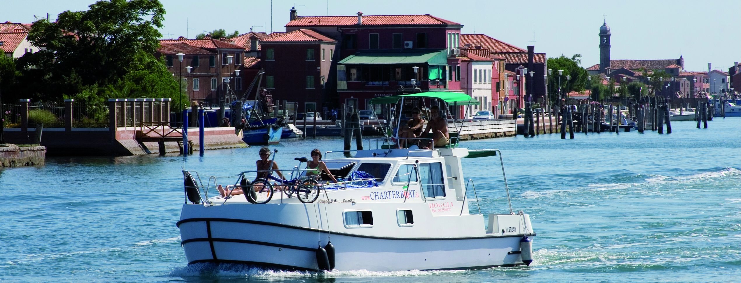Folk om bord i en husbåt i den venetianske lagunen