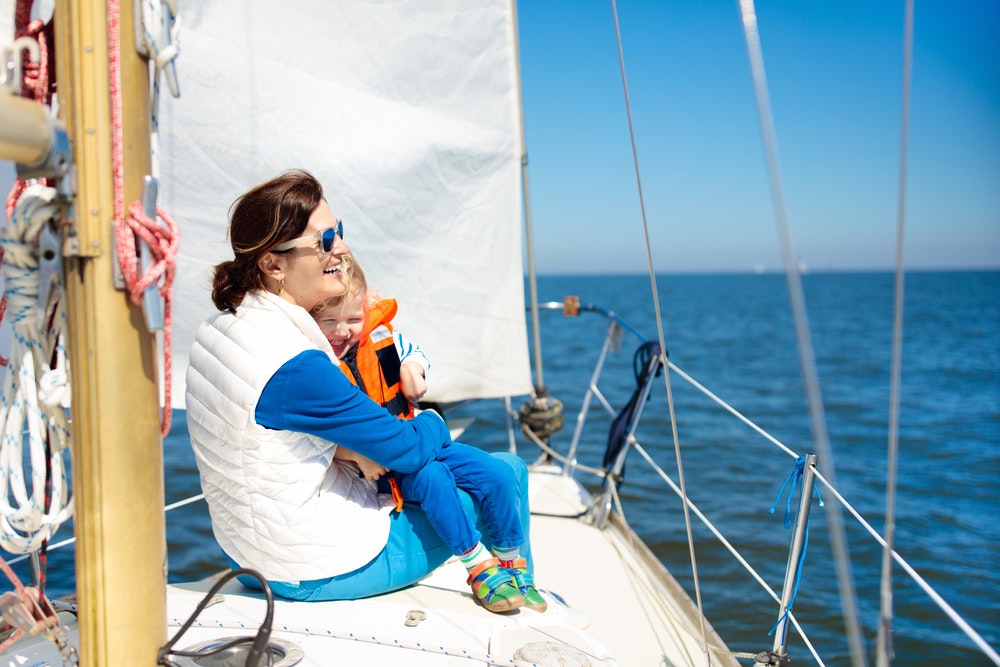 Mother and child in a life jacket sailing on a yacht at sea