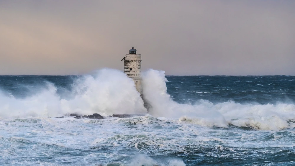 Маяк Манджабарче с большими волнами, разбивающимися о него во время шторма.