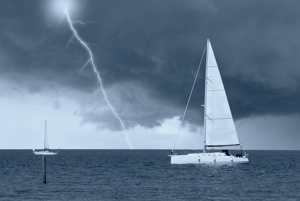 Loď na šírom mori v búrke s bleskami.