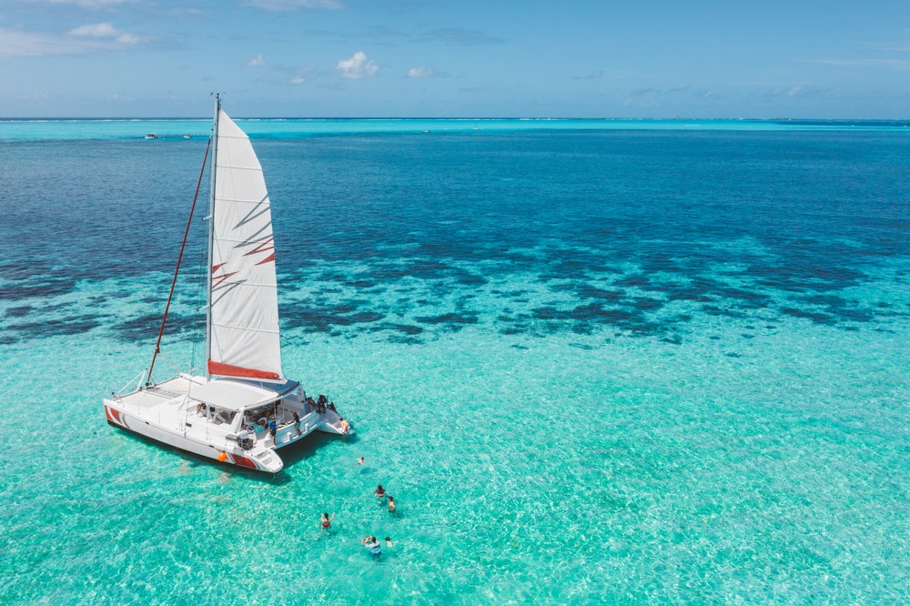 Famille et amis se baignant sur un magnifique catamaran dans un lagon turquoise paradisiaque sur la côte est de l'île Maurice.