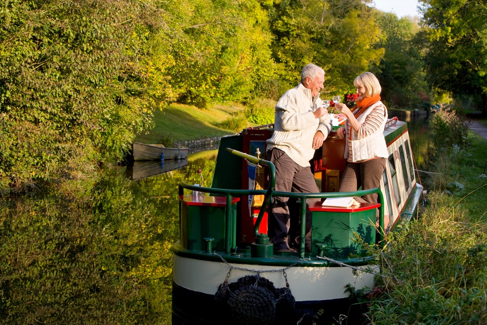Ein älteres Ehepaar auf einem malerischen Hausboot mit einem Glas Wein