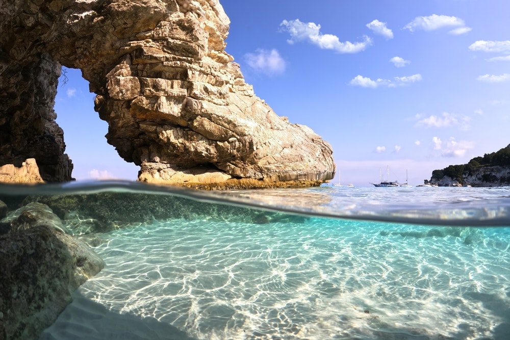 Die Meeresoberfläche geteilt durch Fotos des wunderschönen paradiesischen türkisfarbenen exotischen Strandes von Voutoumi, wahrscheinlich der beste in Griechenland, der ionischen Insel Antipaxos