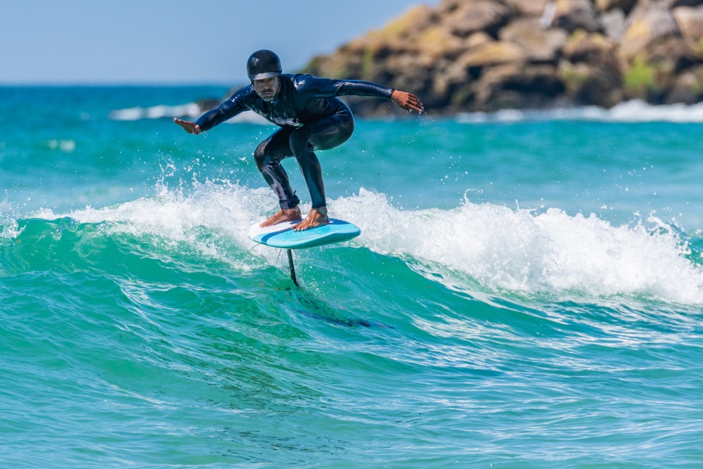 Bărbat pe un val pe o placă de surf din folie. Foilsurfing.