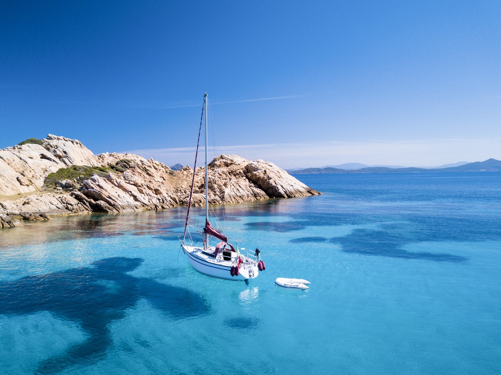 Una barca a vela davanti all'isola di Mortorio in Sardegna. Incredibile spiaggia con mare turchese e trasparente. 