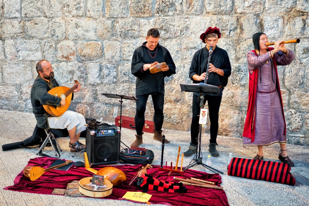 Улични музиканти в старинни костюми пеят и свирят в Стария град на Дубровник