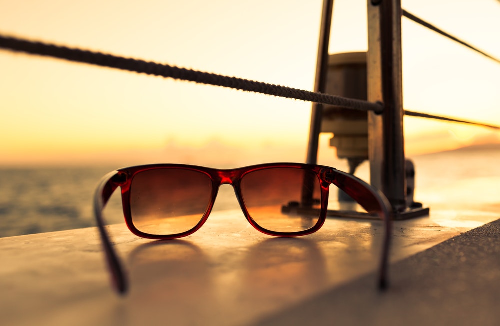 Détail de lunettes de soleil sur un bateau au coucher du soleil.