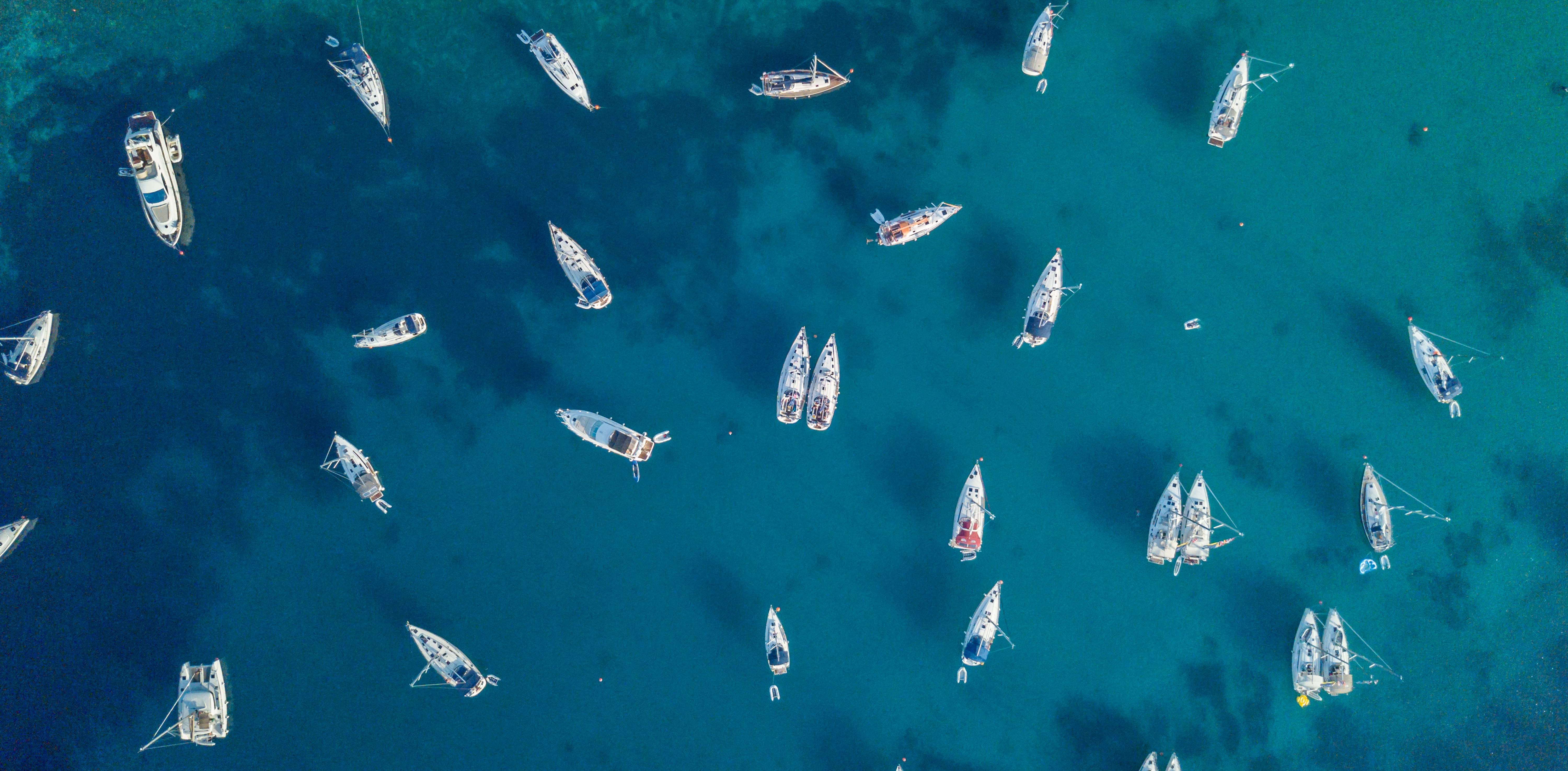 Aerial view of many anchoring yacht in open water. Ocean and sea travel and transportation