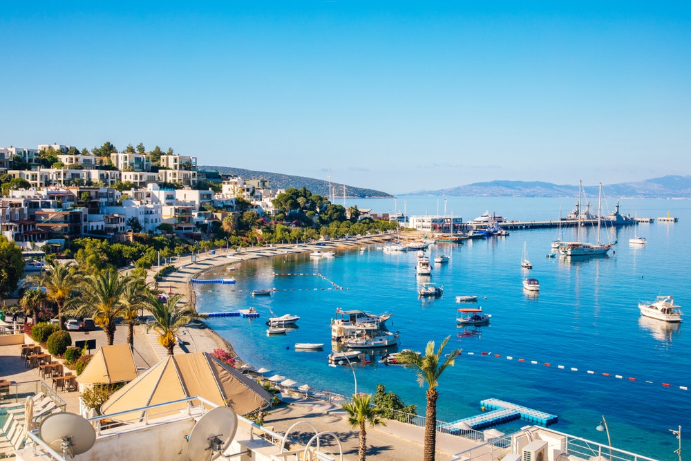 Vista della spiaggia di Bodrum, del Mar Egeo, delle tradizionali case bianche, dei fiori, del porto turistico, delle barche a vela e degli yacht a Bodrum, in Turchia.