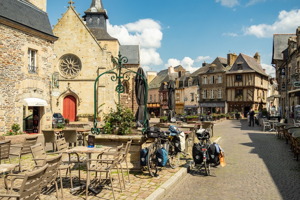 Площадь красивой деревни Малестрот во французской Бретани, велосипеды, ресторан в саду.