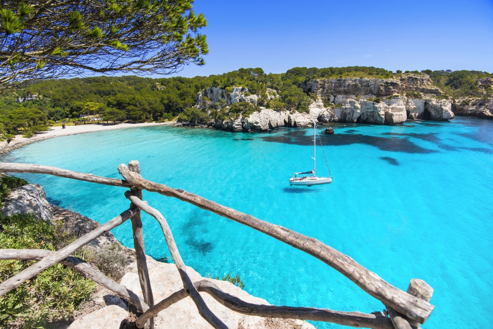 La bellissima spiaggia di Cala Macarella, Isola di Minorca, Spagna. Barca a vela nella baia.