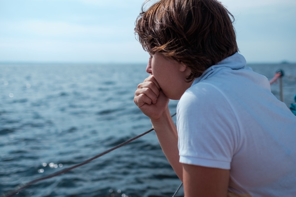 Млада жена страда от морска болест по време на ваканция с лодка