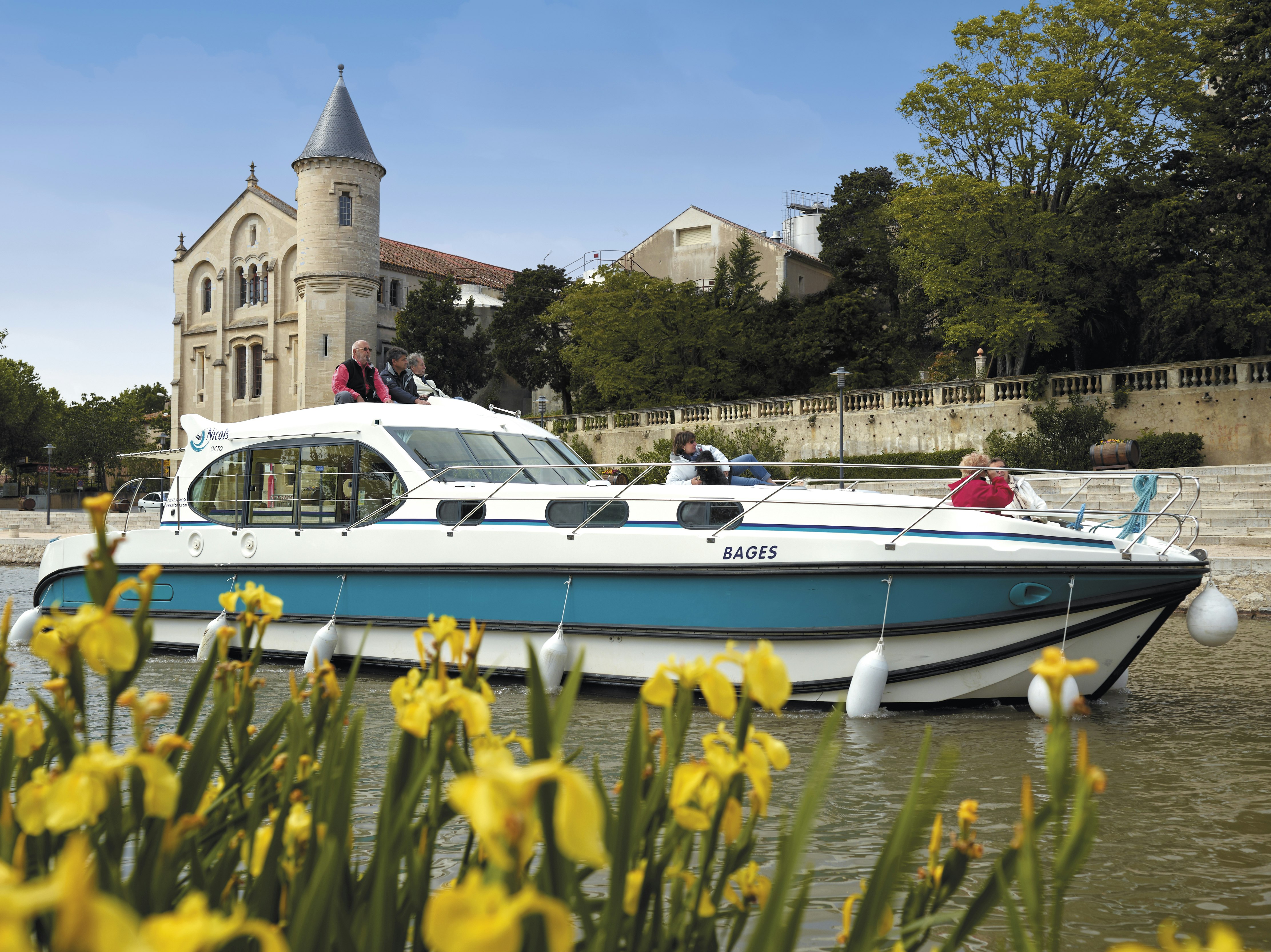 En husbåt seglar förbi ett historiskt slott i Frankrike.