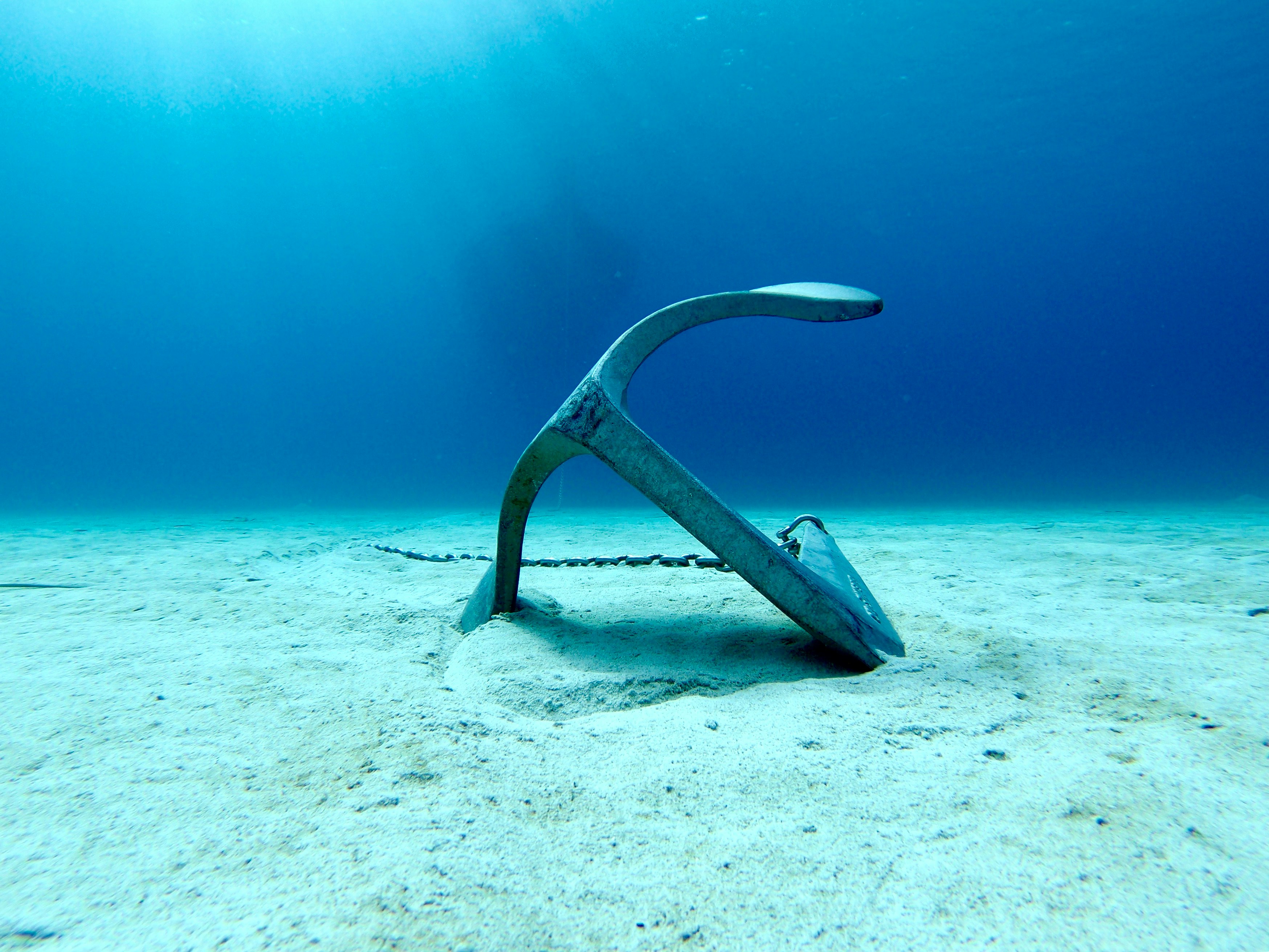 Anchor lying on the sand in the crystal blue waters of the Mediterranean
