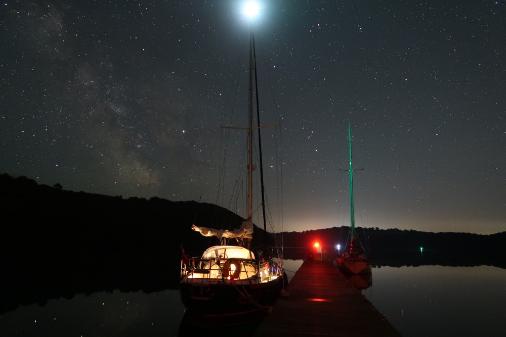 Ночное небо в море с яхтой.