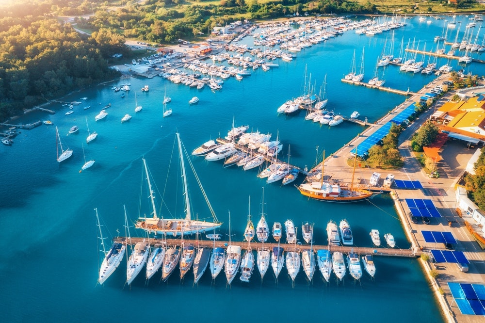 Skats no gaisa uz laivām un luksusa jahtām piestātnēs vasaras saulrieta laikā Pulā, Horvātijā. 