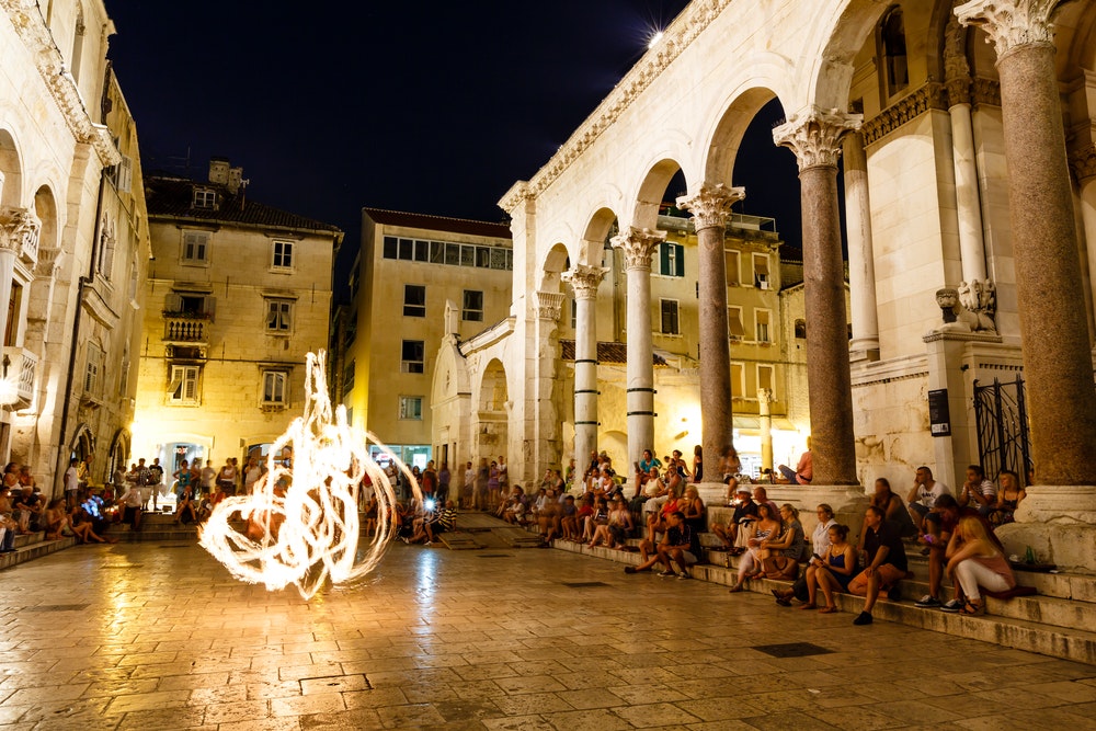 Жонгльор с огън се изявява по време на улично шоу в двореца Диоклециан в Сплит, Хърватия.