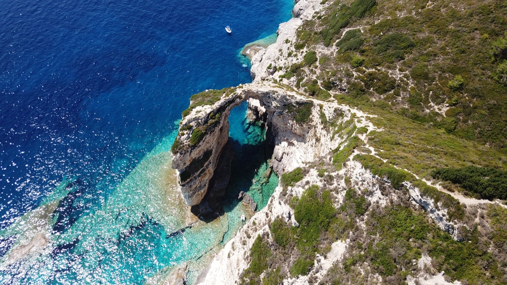 ギリシャ、イオニア海、パクソス島のターコイズブルーの海に浮かぶ岩のアーチを俯瞰したもの。 