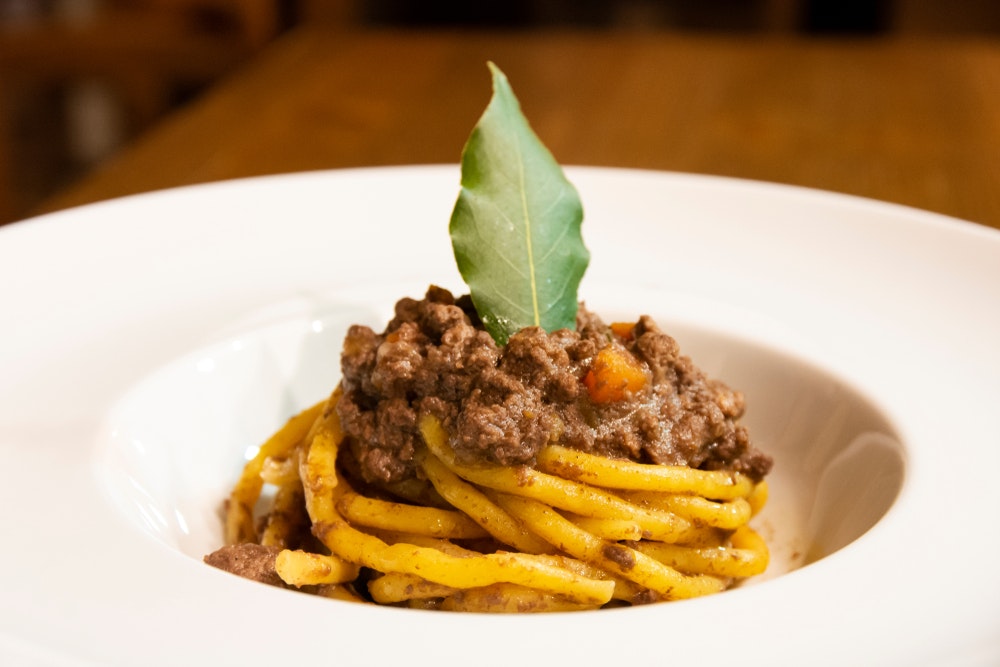 Drveni stol s tjesteninom Bigoli i umakom Amarone (tipično talijansko jelo), crnim vinom i kruhom.