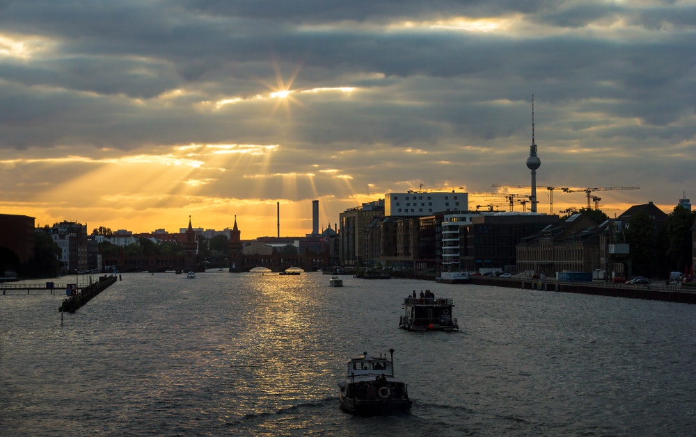 Berlin vid solnedgången, stadssilhuett med utsikt över floden och båtar, husbåtar.