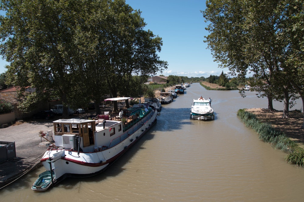  Canal du Midi en el encantador pueblo de Homps en un día soleado.