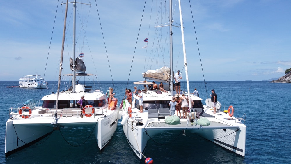 A large number of people resting on catamarans