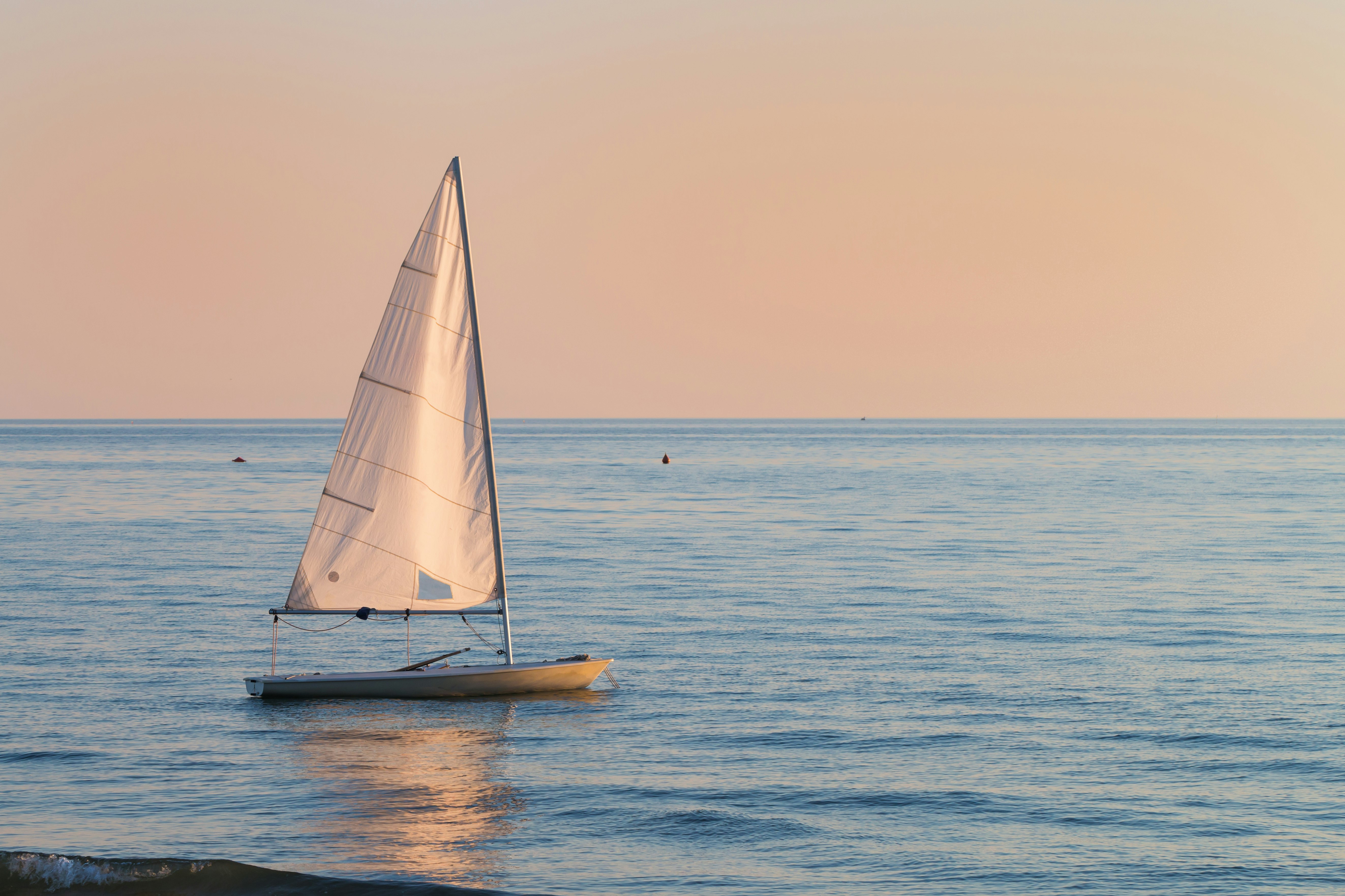 small sailboat in the water small sailboat in the water next to the beach next to the beach in a summer sunset ready to sailing with the last breeze of the day