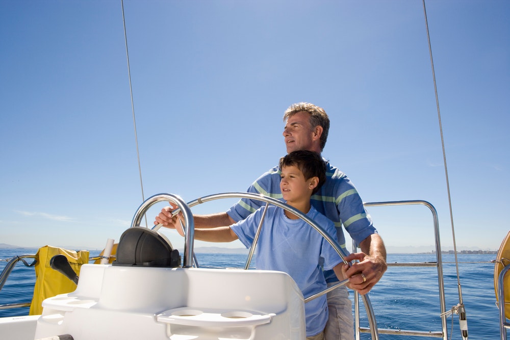 Ένας πατέρας και ένας γιος οδηγούν μια βάρκα μια ηλιόλουστη μέρα.