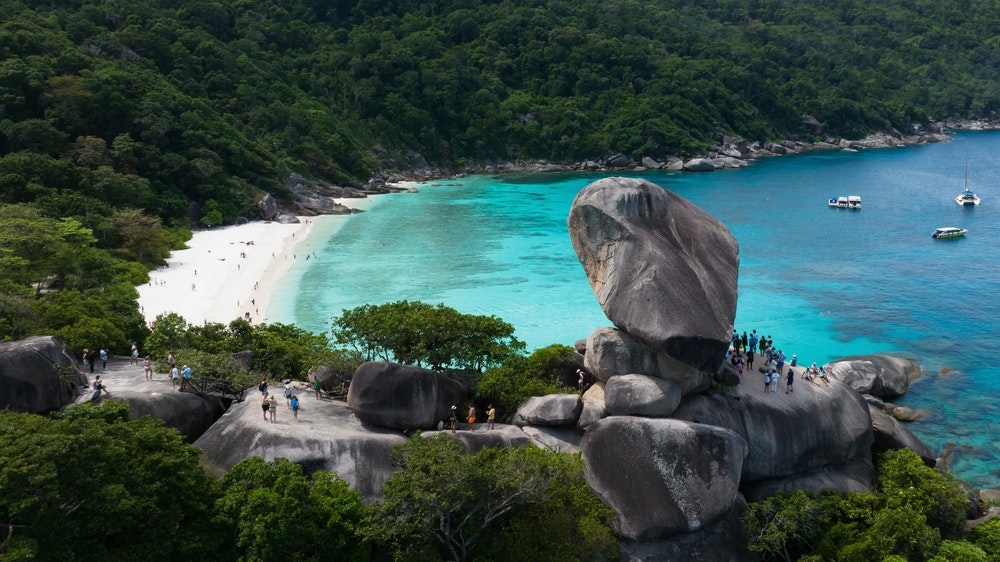 Felsformationen auf den Similan-Inseln, Menschen an einem Aussichtspunkt mit der Bucht im Hintergrund