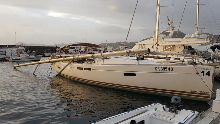 Ein Boot mit einem gebrochenen Mast im Hafen verankert